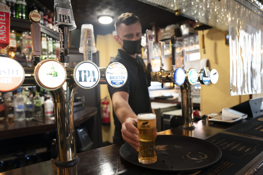 A member of staff serves a drink, as pubs, cafes and restaurants in England reopen indoors under the latest easing of the coronavirus lockdown, in Manchester, England, Monday, May 17, 2021. Pubs and restaurants across much of the U.K. are opening for indoor service for the first time since early January even as the prime minister urged people to be cautious amid the spread of a more contagious COVID-19 variant.