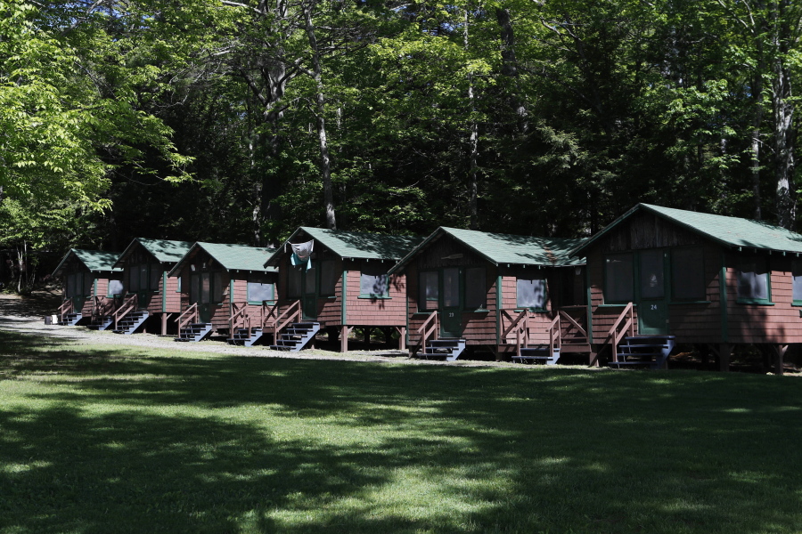 FILE - This Thursday, June 4, 2020 file photo shows a row of cabins at a summer camp in Fayette, Maine. On Friday, May 28, 2021, the Centers for Disease Control and Prevention posted guidance saying kids at summer camps can skip wearing masks outdoors, with some exceptions. Children who aren't fully vaccinated should still wear masks outside when they're in crowds or in sustained close contact with others - and when they are inside, and fully vaccinated kids need not wear masks indoors or outside, the CDC says. (AP Photo/Robert F.