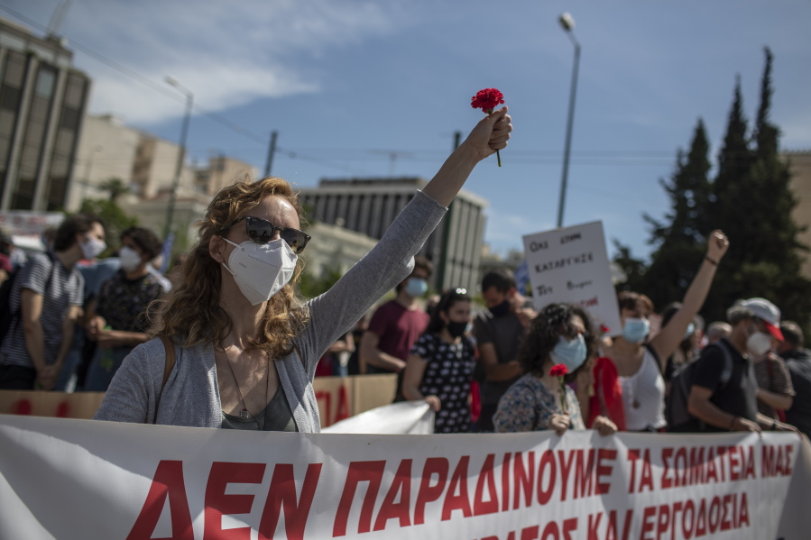 Members of the communist party-affiliated PAME wearing protective face masks hold red carnations, as they protest during a rally commemorating May Day, in Athens, Greece, Thursday, May 6, 2021. Demonstrators took part on a 24-hour strike against a new labour bill presented by the government protests.