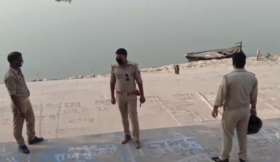This frame grab from video provided by KK Productions shows police officials stand guard at the banks of the river where several bodies were found lying in Ghazipur district in Uttar Pradesh state India, Tuesday, May 11, 2021. Scores of dead bodies have been found floating down the Ganges River in eastern India amid a ferocious surge in coronavirus infections in the country, but authorities said Tuesday they haven't been able to determine the cause of death. Health officials working through the night Monday retrieved 71 bodies, officials in Bihar state said.