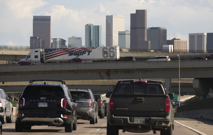 FILE - In this May 27, 2021 file photo, vehicles move along southbound Interstate 25 while motorists sit on the Interstate 70 overpass to start the Memorial Day weekend in Denver.  Americans were hitting the road in near-record numbers at the start of the holiday weekend. More than 1.8 million people went through U.S. airports on Thursday, and that number could top 2 million over the weekend, the highest mark since early March of last year.