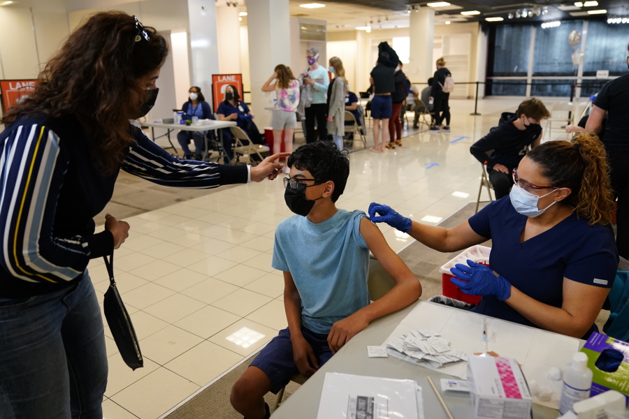 Nouf Albarakati, left, of Narberth Pa., comforts her son Manaf Albarakati, 14, before he receives a Pfizer COVID-19 vaccination from registered nurse Alicia Jimenez at a Montgomery County, Pa. Office of Public Health vaccination clinic at the King of Prussia Mall, Tuesday, May 11, 2021, in King of Prussia, Pa.