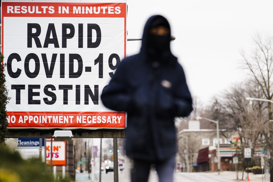 FILE - In this Jan. 25, 2021, file photo, a person wearing face mask as a precaution against the coronavirus walks near a sign advertising a rapid COVID-19 testing site in Philadelphia. U.S. healthy officials say that most fully vaccinated Americans can skip testing for COVID-19, even if they were exposed to someone infected.