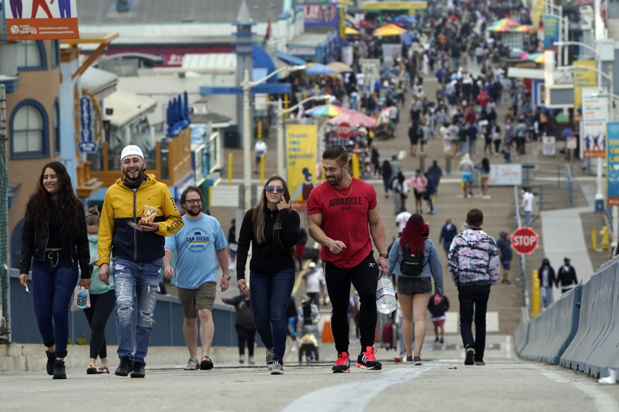FILE - In this May 13, 2021, file photo, May 13, 2021, visitors walk without masks on the pier in Santa Monica, Calif. A number of states immediately embraced new guidelines from the CDC that say fully vaccinated people no longer need to wear masks indoors or out in most situations. But other states - and some businesses -- are taking a wait-and-see attitude.