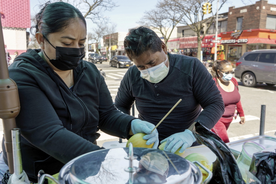 Ruth Palacios and Arturo Xelo, a married couple from Mexico, work at their fruit stand in the Corona neighborhood of the Queens borough of New York on Tuesday, April 13, 2021. They worked seven days a week for months disinfecting COVID-19 patient rooms at the Memorial Sloan Kettering Cancer Center in New York City, but weren't paid overtime Palacios says. The couple filed a federal lawsuit against the contractor that hired them, alleging their pay was cut without their knowledge from $15 an hour to $12.25. They're now selling fruit to make ends meet.