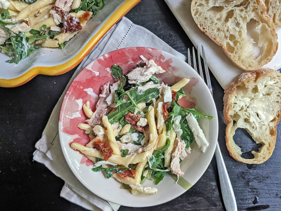 Pasta salad with dried tomatoes, arugula and shredded chicken.