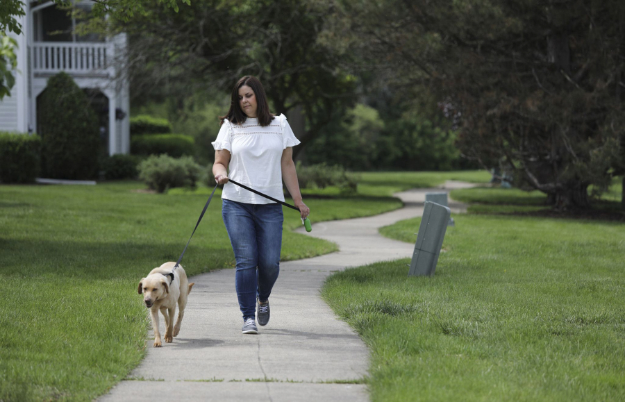 Beth Wawrzaszek, of Naperville, Illinois, takes her dog Summer out for a short walk outside her apartment on May 21, 2021. Wawrzaszek has hired a dog walker to help while she is at work.