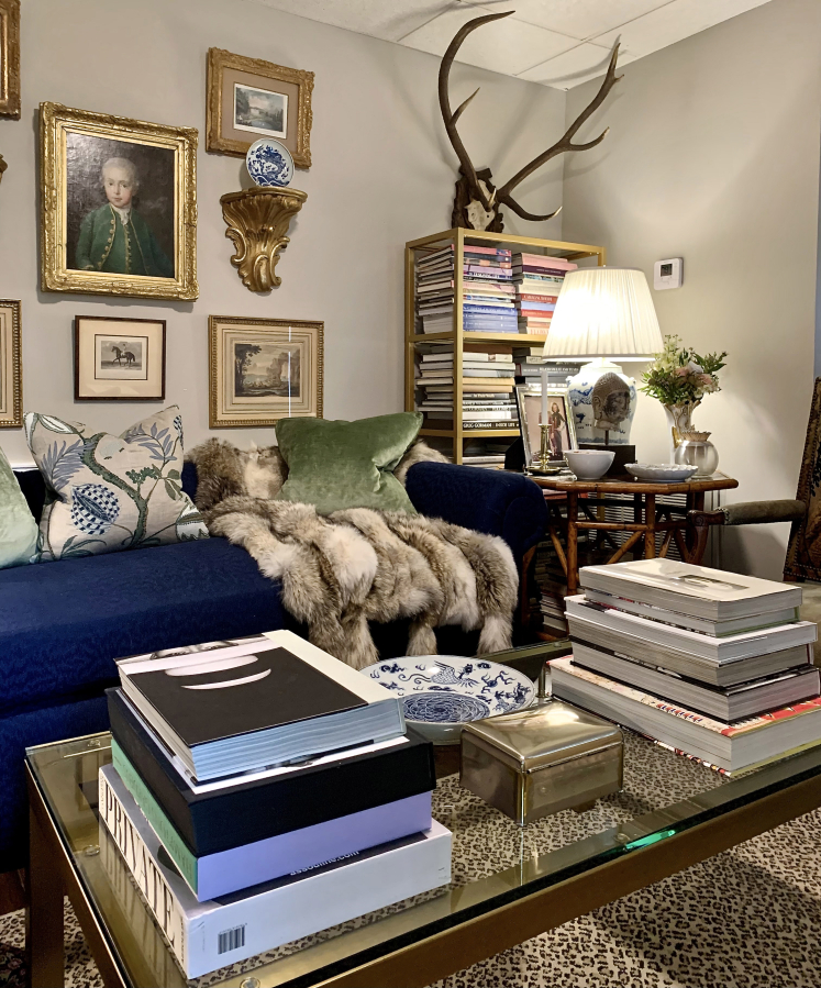 The brass and glass coffee table holds favorite books while allowing the leopard rug to make its presence known in Jim Miller's chic and charming home. Scottish roebuck antlers draw the eye up and add height.