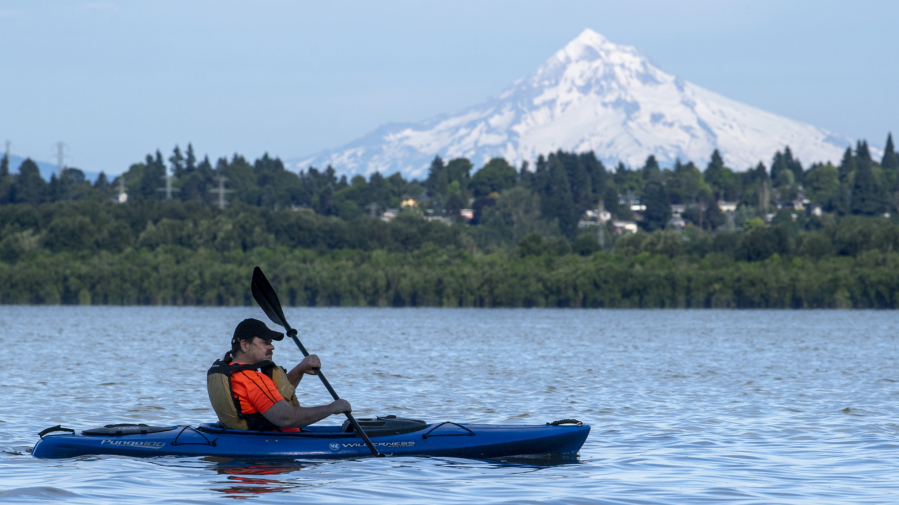 Glenn Wright paddles his kayak through the waters of Vancouver Lake, the snowy flanks of Mt. Hood in the background.
