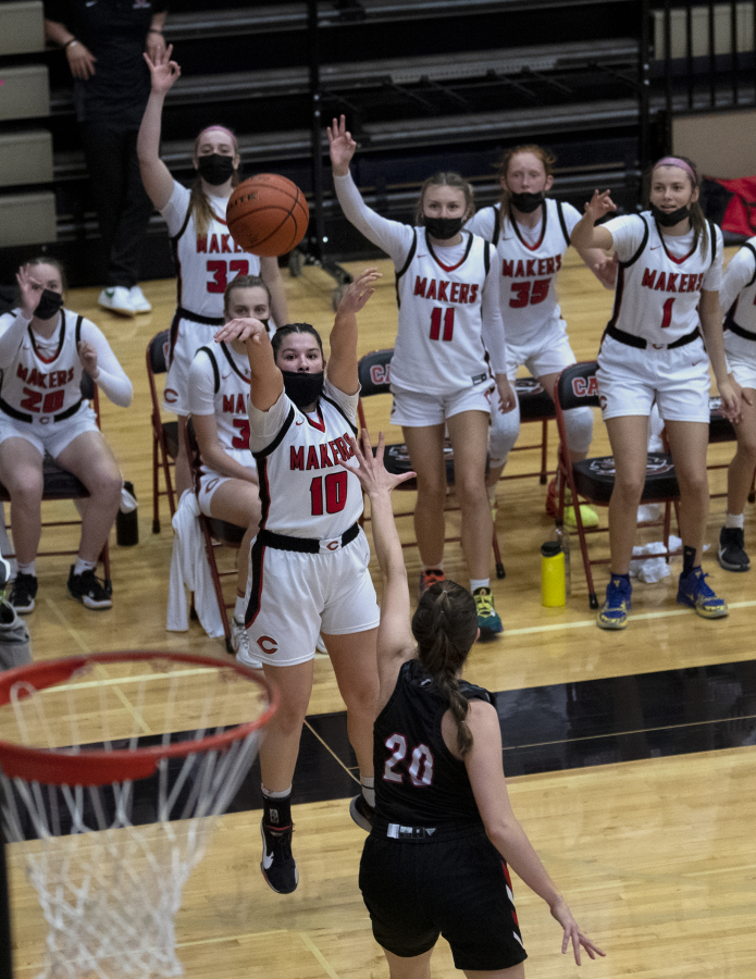 Camas' Katelynn Forner makes a 3-pointer over Union?s Caitlyn Leake while the Papermaker bench celebrates early in the 4A/3A District Championship game on Friday, June 4, 2021, at The Warehouse in Camas. Camas won 77-38.