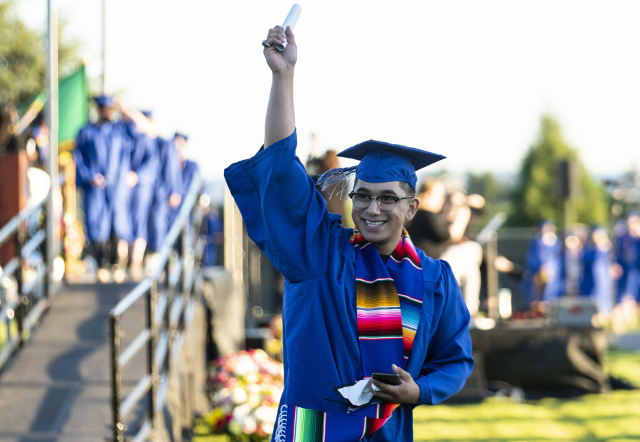 Associate in Arts graduate Alejandro Tapia-Garcia triumphantly holds up his diploma to a crowd watching outside the fence of Kim Christiansen Field on Thursday during the Clark College Commencement ceremony.
