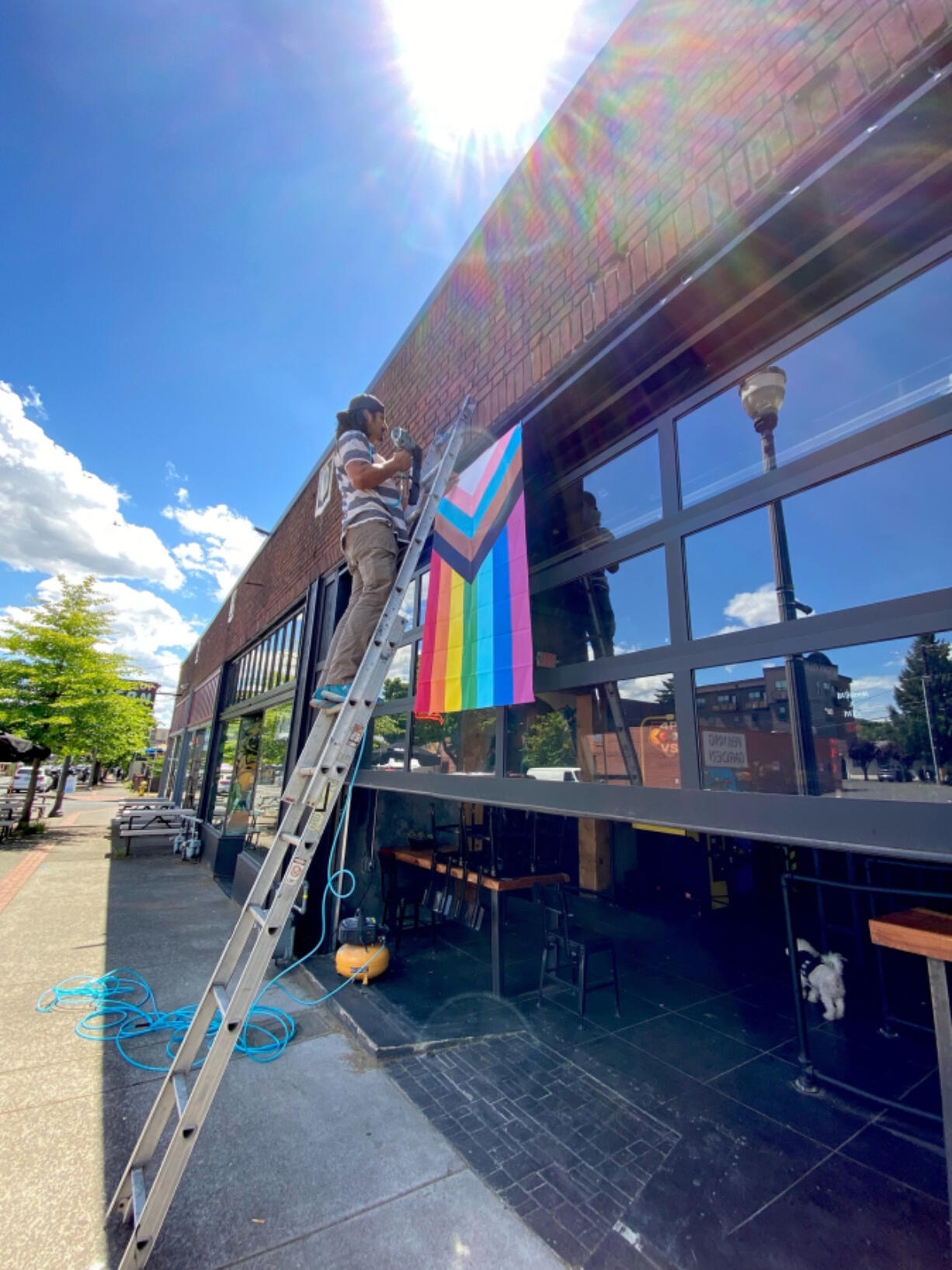 A Thirsty Sasquatch employee hangs new LGBTQ Pride banners Wednesday. Vandals tore down the old banners and smeared feces on the premises.