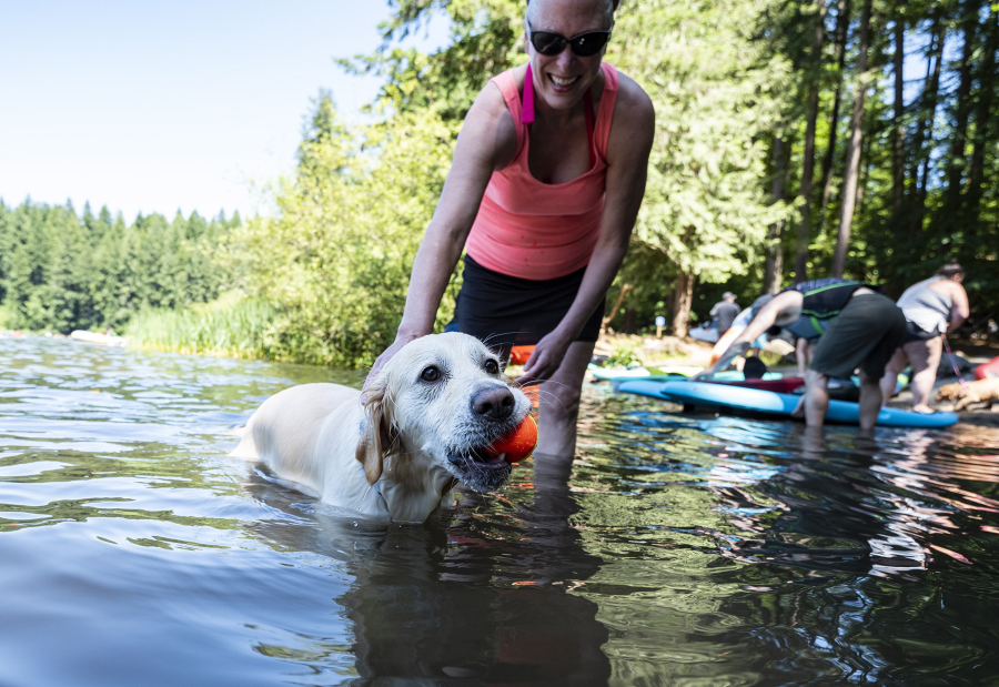 Carolyn Hyink of Tigard, Ore., tries to grab a tennis ball from 5-year-old English cream golden retriever Hannah on Saturday at Battle Ground Lake State Park. Extreme temperatures forecast for this weekend are likely to bring large numbers of people to the water, prompting warnings that rivers and streams still remain dangerously cold.