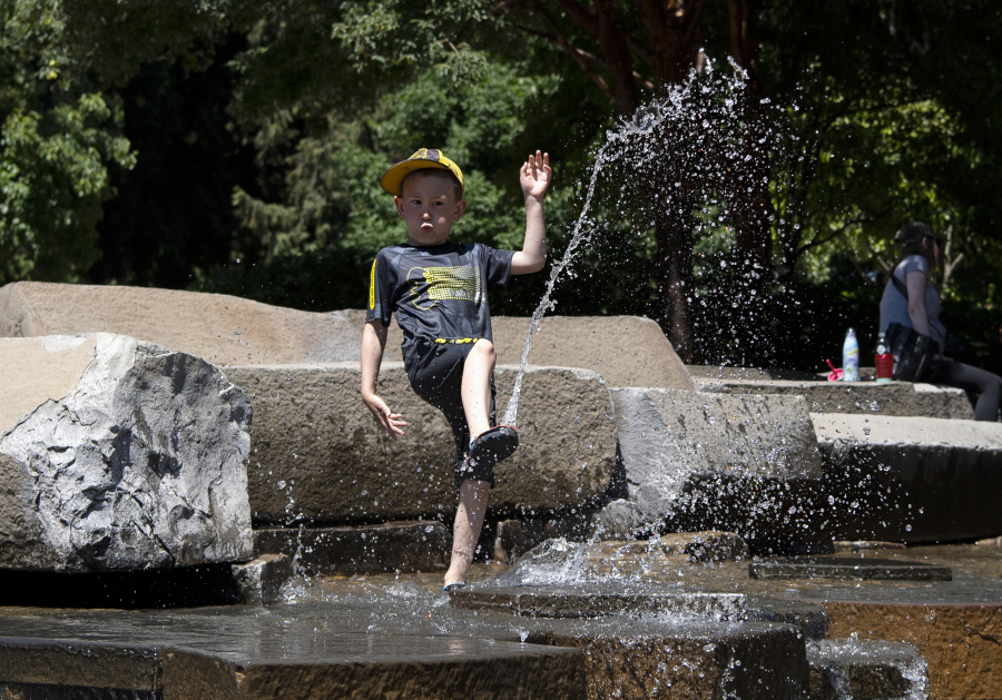 Henry Lester, 5, kicks water on Friday at the water feature in Esther Short Park, which opened on Thursday. Temperatures are expected to climb into the triple digits over the weekend.