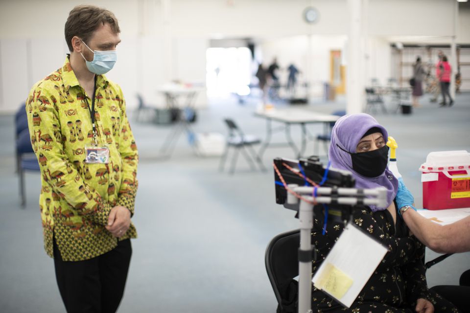 Ulmaskhon Rustamova, right, 56, received her first COVID-19 vaccination at a Multnomah County vaccination clinic in the former Fabric Depot building at Southeast 122nd Avenue in Portland. With her is physician Joseph Eisenberg, left, who works for the county in Gresham. June 16, 2021.