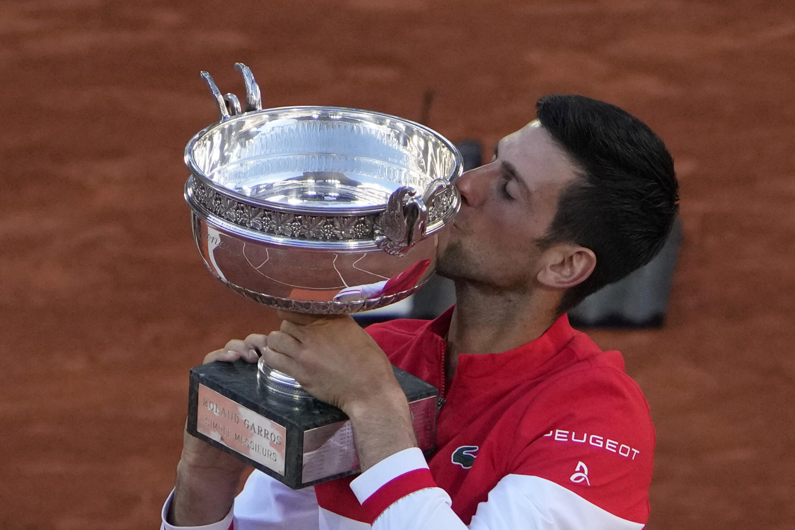 Serbia's Novak Djokovic kisses the cup after defeating Stefanos Tsitsipas of Greece during their final match of the French Open tennis tournament at the Roland Garros stadium Sunday, June 13, 2021 in Paris. Djokovic won 6-7, 2-6, 6-3, 6-2, 6-4.