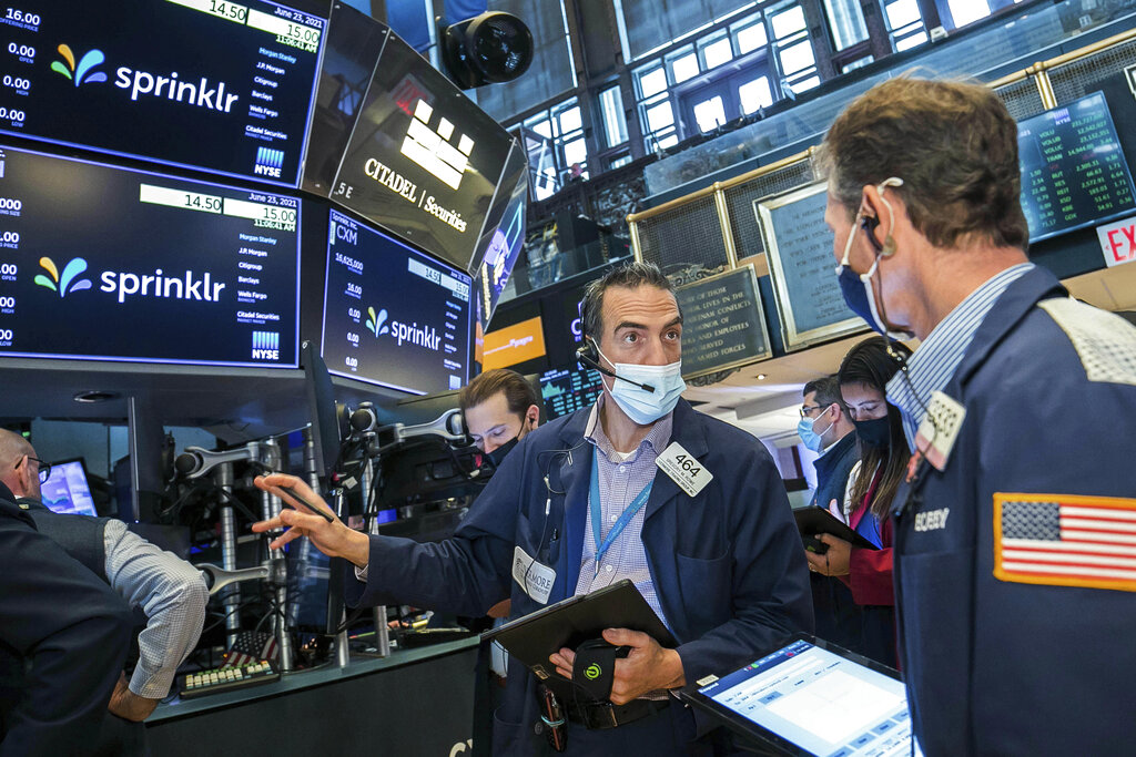 In this photo provided by the New York Stock Exchange, Gregory Rowe, center, talks with a fellow trader on the NYSE trading floor, Wednesday, June 23, 2021. A morning gain on Wall Street was fading away at midday Wednesday, leaving major indexes mixed. Investors are still trying to parse emerging signs of inflation and judge whether they will be transitory, as the Federal Reserve thinks they will.