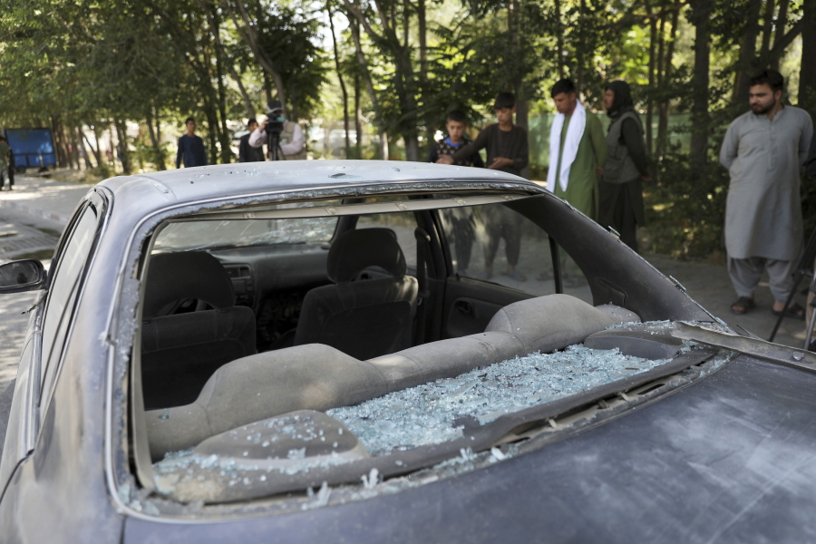 Afghan men look at a damage car after a roadside bomb explosion in Kabul, Afghanistan, Sunday, June 6, 2021.