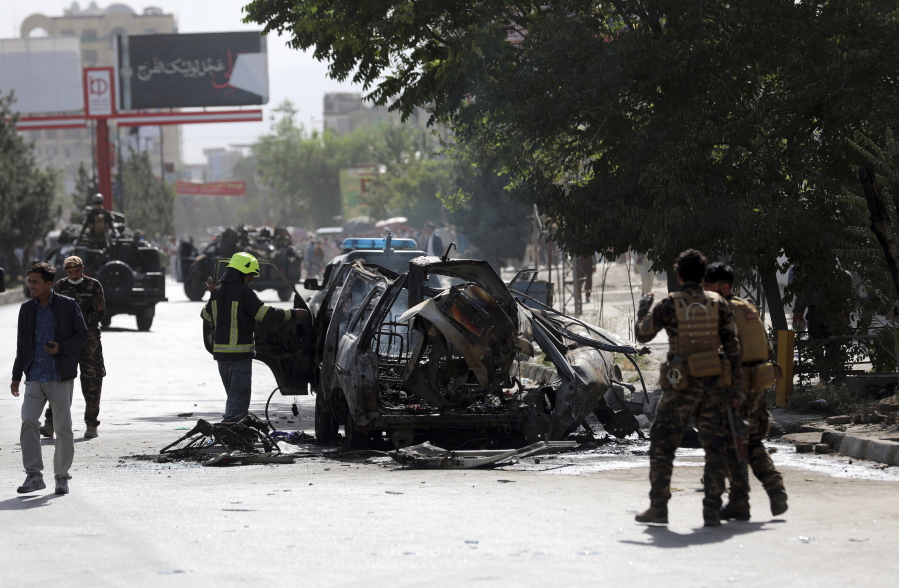 Afghan security personnel inspect the site of a bomb explosion in Kabul, Afghanistan, Saturday, June 12, 2021. Separate bombs hit two minivans in a mostly Shiite neighborhood in the Afghan capital Saturday, killing several people and wounding others, the Interior Ministry said.