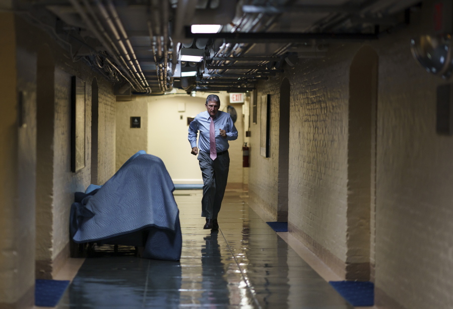 FILE - In this June 16, 2021, file photo Sen. Joe Manchin, D-W.Va., one of the key Senate infrastructure negotiators, rushes back to a basement room at the Capitol as he and other Democrats work behind closed doors, in Washington. Congress is hunkered down, grinding through an eight-week stretch as the president's Democratic allies in the House and Senate try to shape his big infrastructure ideas into bills that could actually be signed into law. Perhaps not since the drafting of Obamacare more than a decade ago has Washington tried a legislative lift as heavy as this. (AP Photo/J.
