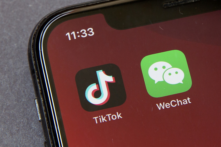 FILE - Icons for the smartphone apps TikTok and WeChat are seen on a smartphone screen in Beijing, in a Friday, Aug. 7, 2020 file photo.  Officials say the White House has dropped Trump-era executive orders that attempted to ban the popular apps TikTok and WeChat and will conduct its own review aimed at identifying national security risks with software applications tied to China. A new executive order directs the Commerce Department to undertake what officials describe as an "evidence-based" analysis of transactions involving apps that are manufactured or supplied or controlled by China. Officials are particularly concerned about apps that collect users' personal data or have connections to Chinese military or intelligence activities.