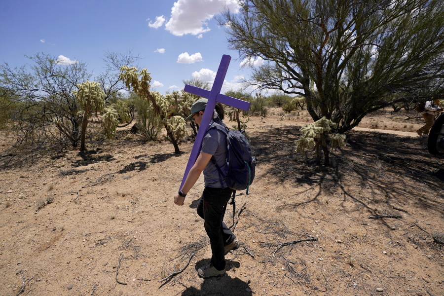Alyssa Quintanilla, part of the Tucson Samaritans volunteer group, carries a cross May 18 to be installed at the site of the migrant who died in the desert some time ago in the desert near Three Points, Ariz. (Photos by Ross D.