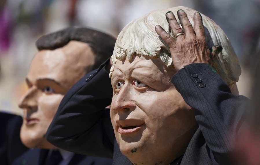 Protestors wearing giant heads portraying G7 leaders British Prime Minister Boris Johnson, right, and French President Emmanuel Macron participate in a demonstration on a beach outside the G7 meeting in St. Ives, Cornwall, England, Sunday, June 13, 2021. Leaders of the G7 wrap up three days of meetings in Carbis Bay Sunday, in which they discussed such topics as COVID-19, climate, foreign policy and the economy.