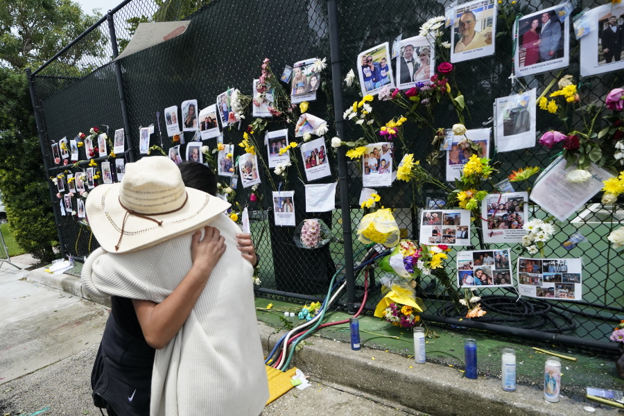 People embrace at a make-shift memorial outside St. Joseph Catholic Church, in Surfside, Fla., Monday, June 28, 2021, near the collapsed building for people still missing or dead. Many people were still unaccounted for after Thursday's fatal collapse.