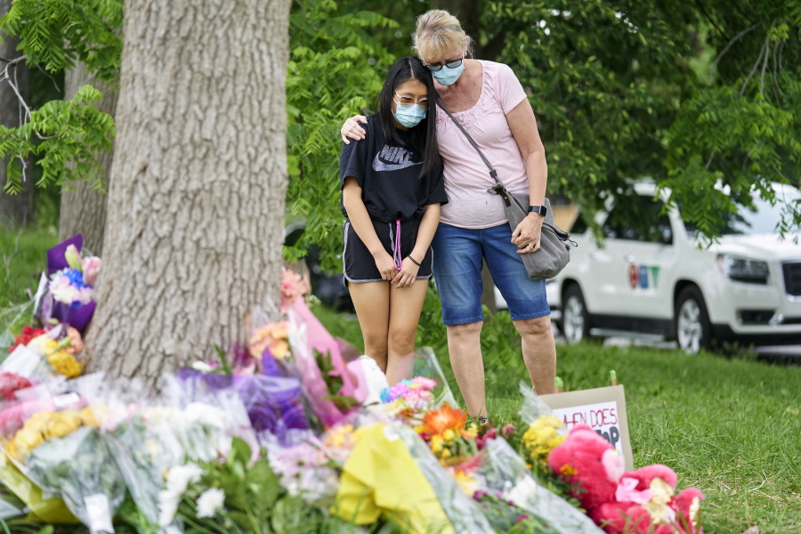 Mourners take a moment to reflect at the scene of an attack on Monday, involving a driver accused of plowing a pickup truck into an immigrant family of five in London, Ontario, Tuesday, June 8, 2021.  Canadian Prime Minister Justin Trudeau has denounced the attack as police say the attack targeted Muslims.