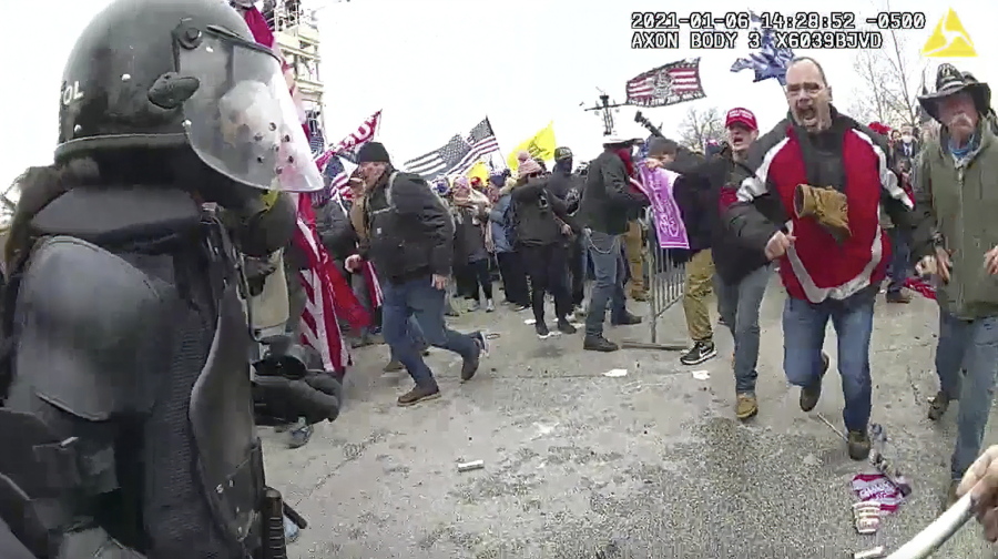 This still frame from Metropolitan Police Department body worn camera video shows Thomas Webster, in red jacket, at a barricade line at on the west front of the U.S. Capitol on Jan. 6, 2021, in Washington. Webster, a Marine Corps veteran and retired New York City Police Department Officer, is accused of assaulting an MPD officer with a flagpole. A number of law enforcement officers were assaulted while attempting to prevent rioters from entering the U.S. Capitol.