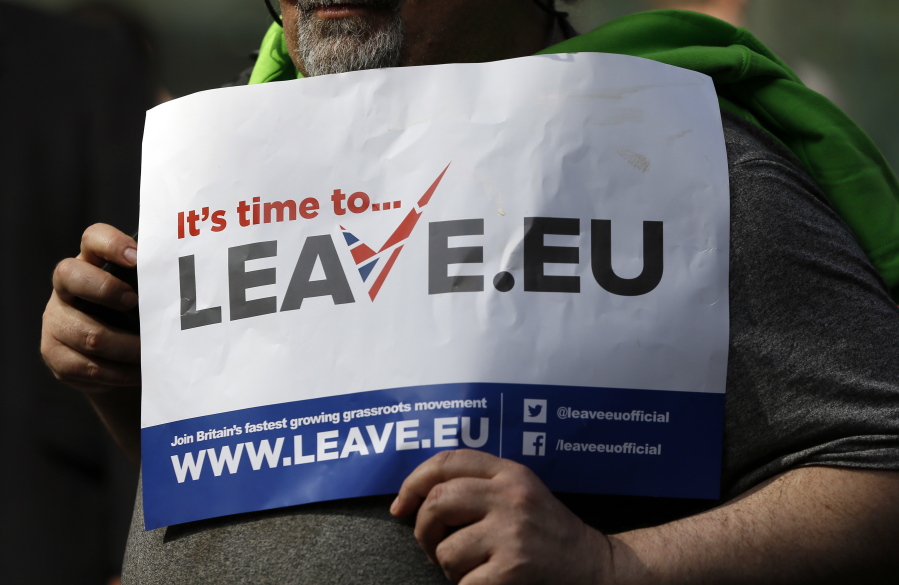 FILE - In this Thursday, March 31, 2016 file photo, a 'Leave' supporter holds a banner near the Electoral Commission, in London.  Five years ago, Britons voted in a referendum that was meant to bring certainty to the U.K.'s fraught relationship with its European neigbors. Voters' decision on June 23, 2016 was narrow but clear: By 52 percent to 48 percent, they chose to leave the European Union. It took over four years to actually make the break. The former partners are still bickering, like many divorced couples, over money and trust.