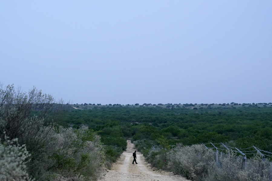 FILE - In this May 11, 2021, file photo a Border Patrol agent walks along a dirt road near the U.S.-Mexico border, in Roma, Texas. The Biden administration says families arriving at the U.S. border with Mexico will have their cases fast-tracked in immigration court, an announcement on Friday, May 28, that comes less than two weeks after said it was easing pandemic-related restrictions on seeking asylum. Under the plan, immigration judges in 10 cities will aim to decide cases within 300 days.