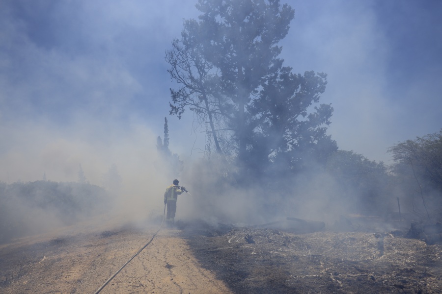 An Israeli firefighter attempts to extinguish a fire caused by an incendiary balloon launched by Palestinians from the Gaza Strip, on the Israel-Gaza border, Israel, Tuesday, June 15, 2021.