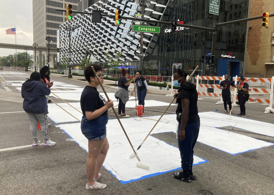 Students from University Prep Art Design celebrate Juneteenth by repainting a street mural, "Power To The People," in downtown Detroit on Saturday,  June 19, 2021.