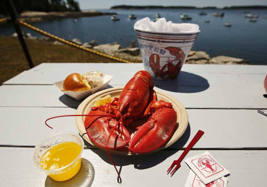 FILE - In this Thursday, July 19, 2018, file photo, a lobster is served waterfront at McLoon's Lobster Shack in Spruce Head, Maine. Consumers who are headed back to seafood restaurants and markets for the first time in months will find at a premium due to a limited supply. (AP Photo/Robert F.