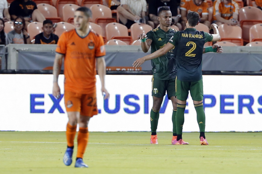 Houston Dynamo midfielder Matias Vera (22) walks off as Portland Timbers Jeremy Ebobisse, middle, and Jose van Rankin (2) celebrate the goal by Ebobisse during the second half of an MLS soccer match Wednesday, June 23, 2021, in Houston.