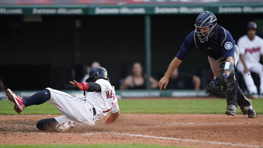 Cleveland Indians' Cesar Hernandez, left, scores as Seattle Mariners catcher Tom Murphy is late on the tag in the 10th inning of a baseball game, Saturday, June 12, 2021, in Cleveland.