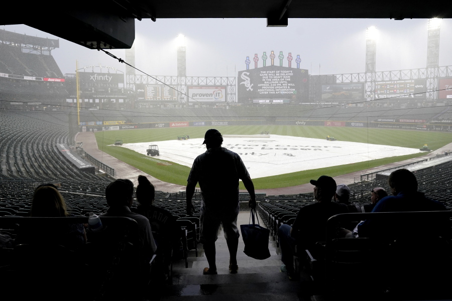 A tarp covers the infield as fans wait during a rain delay before a baseball game between the Seattle Mariners and the Chicago White Sox in Chicago, Saturday, June 26, 2021. (AP Photo/Nam Y.