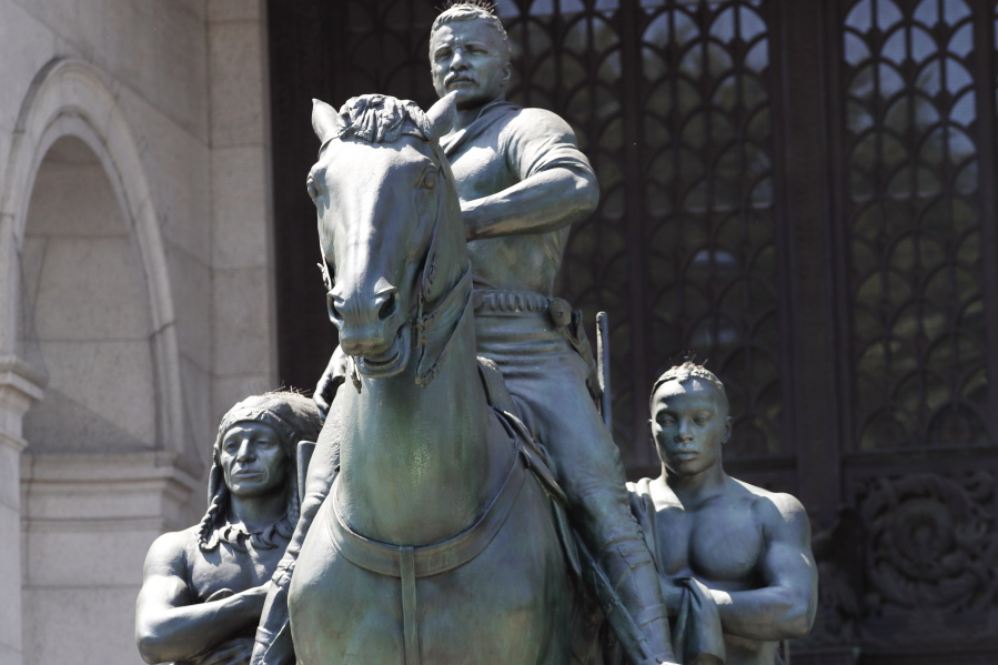 FILE -- In this June 22, 2020 file photo, a statue of Theodore Roosevelt on horseback guided by a Native American man, left, and an African man, right, sits in front of the American Museum of Natural History, in New York. The New York City Public Design Commission voted unanimously Monday, June 21, 2021, to relocate the statue to a yet-to-be-designated cultural institution dedicated to Roosevelt's life and legacy.