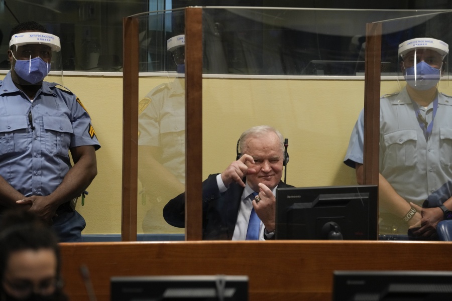 Former Bosnian Serb military chief Ratko Mladic imitates taking pictures as he sits the court room in The Hague, Netherlands, Tuesday, June 8, 2021, where the United Nations court delivers its verdict in the appeal of Mladic against his convictions for genocide and other crimes and his life sentence for masterminding atrocities throughout the Bosnian war.