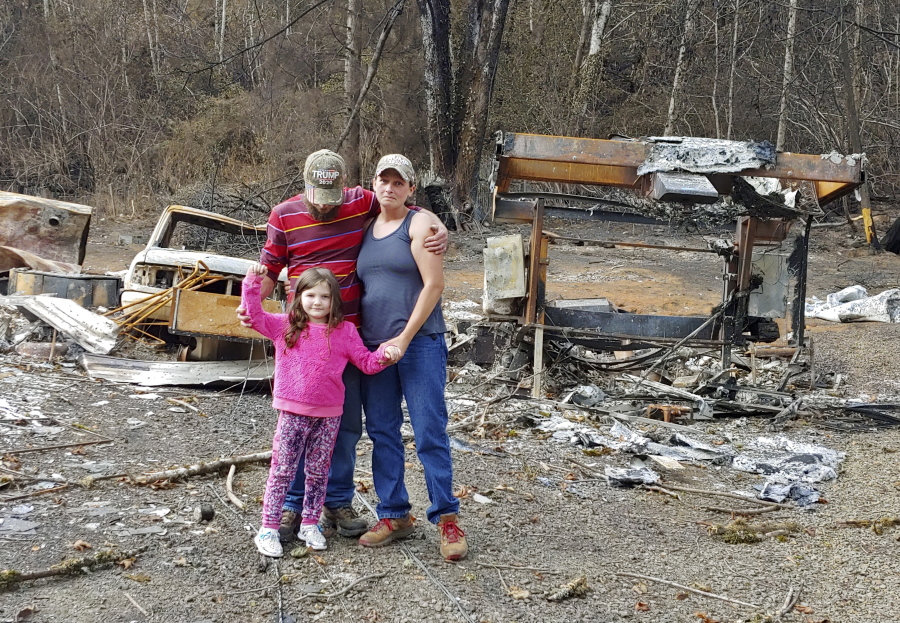 In this photo provided by Tye and Melynda Small, they are seen standing with their 5-year-old daughter, Madalyn, in front of the ruins of their home in Otis, Oregon after the Echo Mountain Fire swept through, burning nearly 300 homes, in September, 2020. The Smalls had to take Madalyn back to their property to help her understand why they couldn't go home. Oregon's unprecedented wildfire season last fall burned 4,000 homes and more than 1 million acres in areas that aren't normally associated with wildfire. Experts say the 2020 wildfire season in Oregon was a taste of what lies ahead as climate change makes blazes more likely and more destructive even in wetter, cooler climates like the Pacific Northwest.