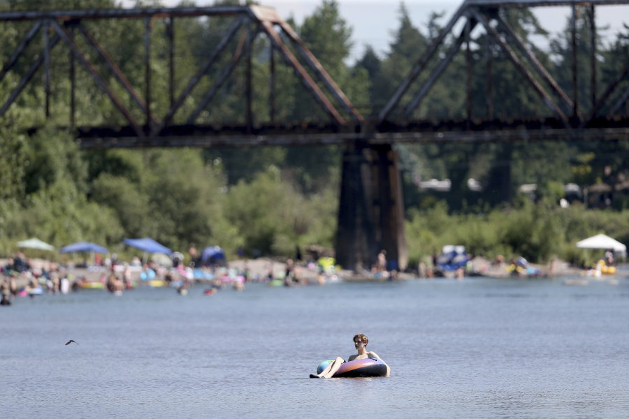 People gather at the Sandy River Delta in Oregon to cool off Friday. Gov. Kate Brown has announced that social distancing rules, capacity limits and most mask mandates will be lifted by June 30. Officials say this weekend's heat likely will impact vaccination efforts.
