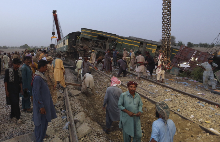 Railway workers rebuild the track at the track at the site of a train collision in the Ghotki district, southern Pakistan, Monday, June 7, 2021. An express train barreled into another that had derailed in Pakistan before dawn Monday, killing dozens of passengers, authorities said. More than 100 were injured, and rescuers and villagers worked throughout the day to search crumpled cars for survivors and the dead.