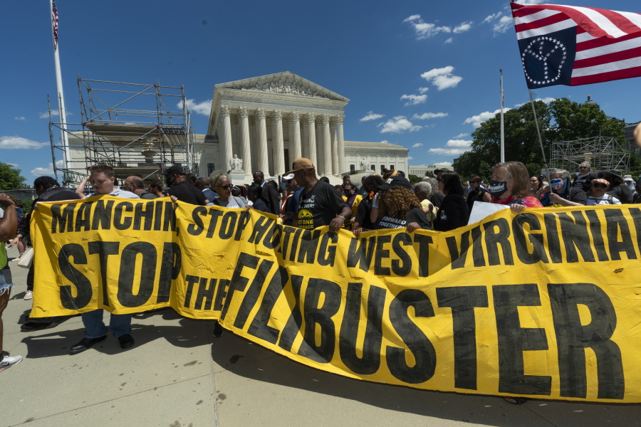 Protesters hold banners as they march from the U.S. Supreme Court, to the Hart Senate Office building in Washington, Wednesday, June 23, 2021, announcing a "Moral March on Manchin and McConnell" and highlighting the right to vote and living wages.