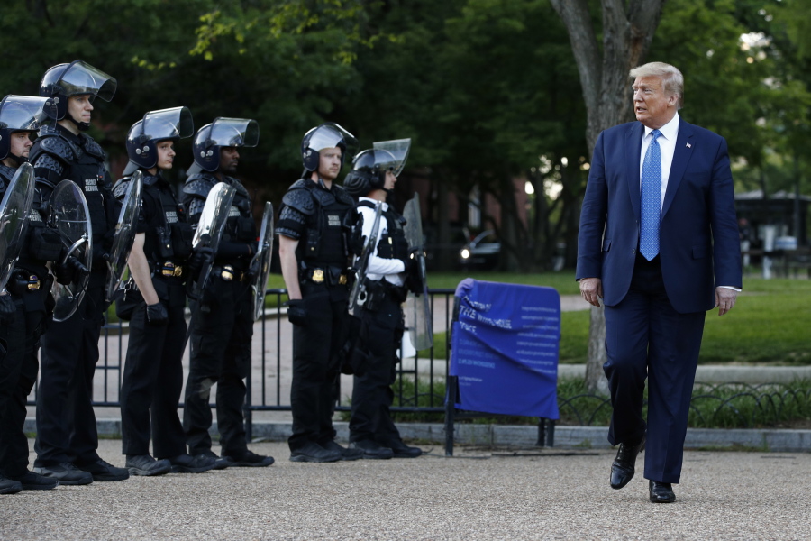 FILE - In this June 1, 2020 file photo, President Donald Trump walks past police in Lafayette Park after visiting outside St. John's Church across from the White House in Washington. An internal investigation has determined that the decision to clear racial justice protestors from an area in front of the White House last summer was not influenced by then-President Donald Trump's plans for a photo opportunity at that spot. The report released Wednesday by the Department of Interior's Inspector General concludes that the protestors were cleared by U.S. Park Police on June 1 of last year so new fencing could be installed.