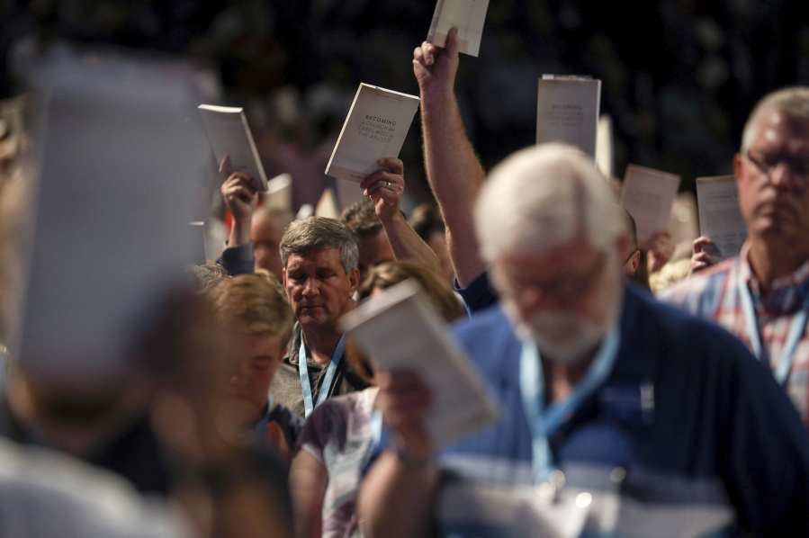 FILE - In this Wednesday, June 12, 2019 file photo, Bill Golden, and thousands of others, hold up copies of a training handbook related to sexual abuse within Southern Baptist churches during a speech by SBC President J. D. Greear on the second day of the SBC's annual meeting in Birmingham, Ala. As Southern Baptists prepare for their biggest annual meeting in more than a quarter-century in June 2021, accusations that leaders have shielded churches from claims of sexual abuse and simmering tensions around race threaten to once again mire the nation's largest Protestant denomination in a conflict that can look more political than theological.
