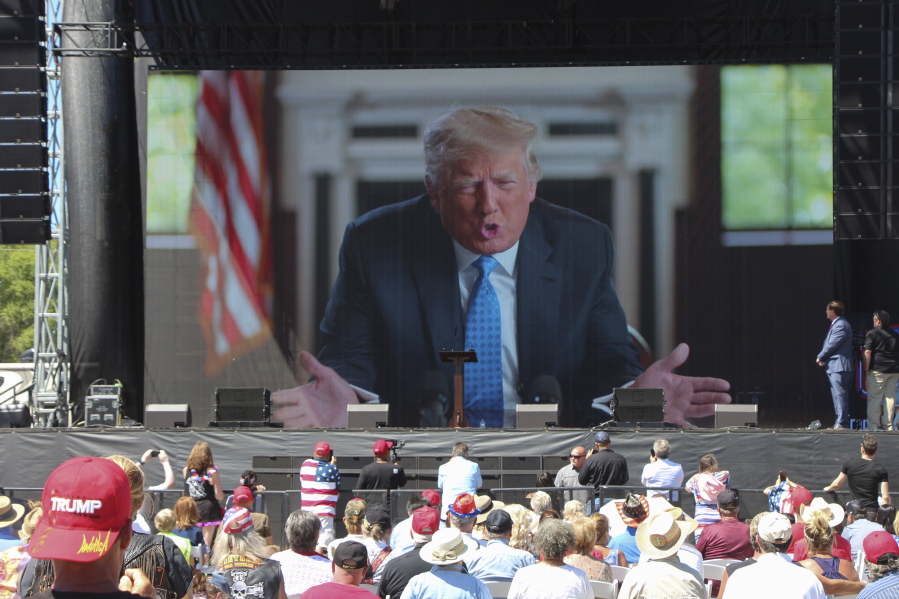 Former President Donald Trump addresses the crowd via video Saturday, June 12, 2021, at the River's Edge Apple River Concert Venue in New Richmond, Wis. The MAGA rally was organized by pillow salesman-turned conspiracy peddler Mike Lindell. For a few hours last weekend, thousands of Donald Trump's loyal supporters came together under the blazing sun in a field in Western Wisconsin to live in an alternate reality where the former president was still in office -- or would soon return.