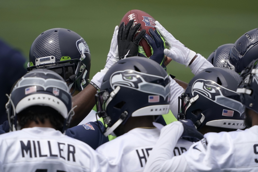 Seattle Seahawks defensive players touch the football during a huddle at NFL football practice Tuesday, June 15, 2021, in Renton, Wash. (AP Photo/Ted S.