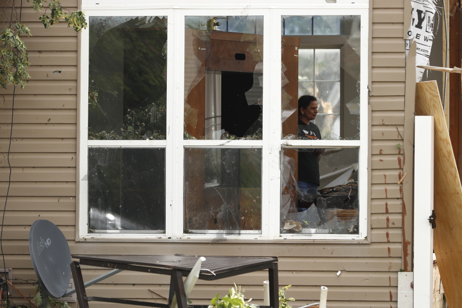 A household member of a damaged house is seen through a broken window after a tornado passed through the area, Monday, June 21, 2021, in Naperville, Ill.
