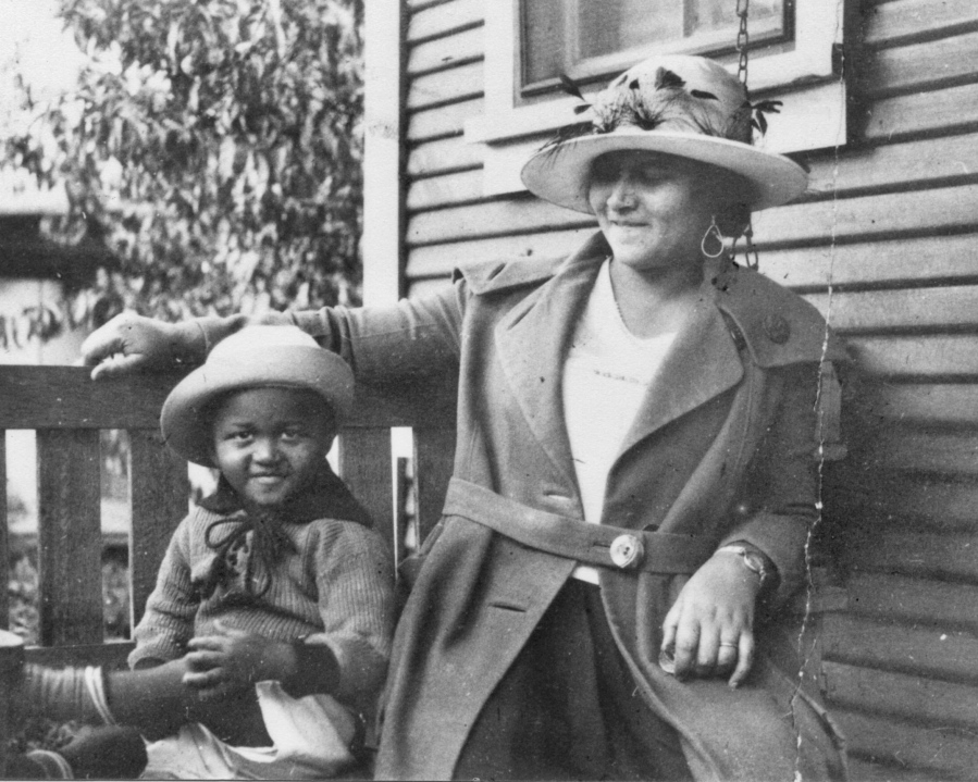 This photo provided by the Department of Special Collections, McFarlin Library, The University of Tulsa shows an African American woman and girl sitting on a porch swing, both dressed in coats and hats, by the side of a house. Provenance is unknown; however, it is believed that these photos were taken in Tulsa, Okla. prior to the Tulsa Race Massacre.
